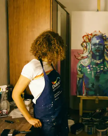 a girl staring at her artwork wearing a blue coverall